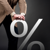 Bank OF Canada rate cuts impact home owners, real estate investors, and mortgage funds. Photo of a man pushing down on a percentage symbol to symbolize the recent rate cuts on mortgages from Bank of Canada